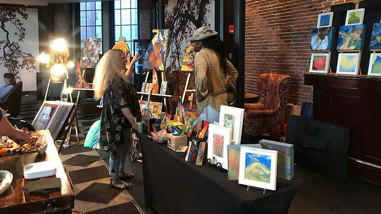 A wide shot of people viewing artwork at an indoor art exhibit A wide shot of people viewing artwork at an indoor art exhibit