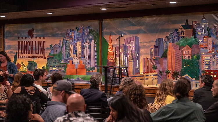A wide shot of an audience waiting for a comedy show in a comedy club.