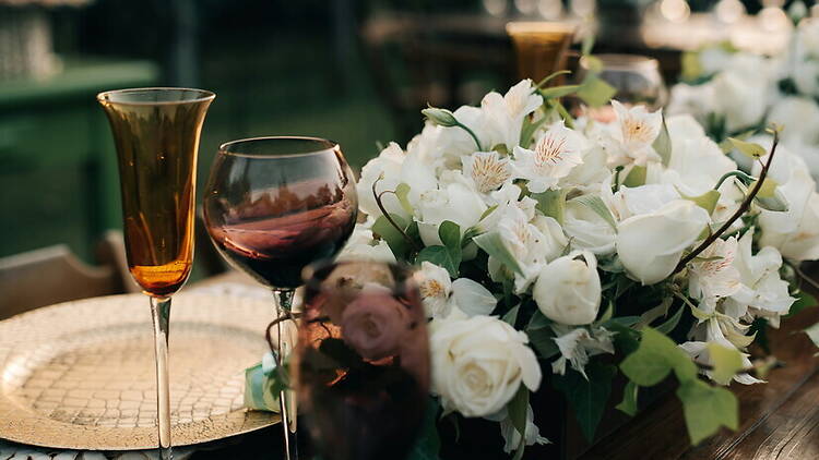 A close-up of floral arrangements and glassware on a decorated outdoor table. A close-up of floral arrangements and glassware on a decorated outdoor table.