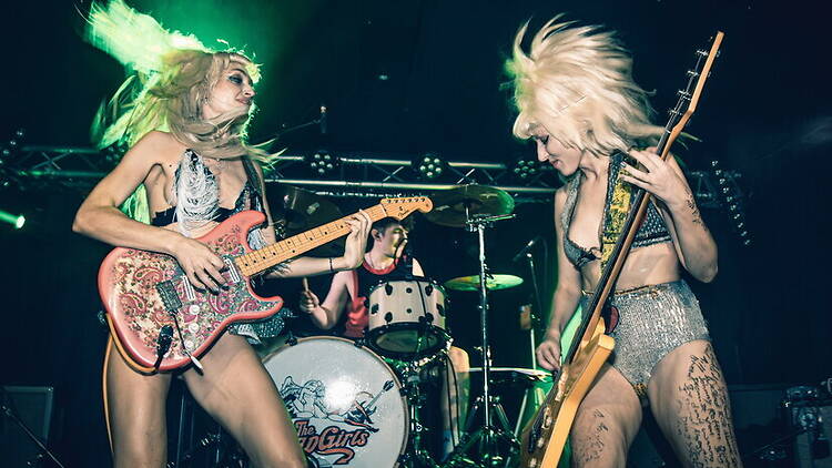 A wide shot of a rock band performing on stage during a live concert. A wide shot of a rock band performing on stage during a live concert.