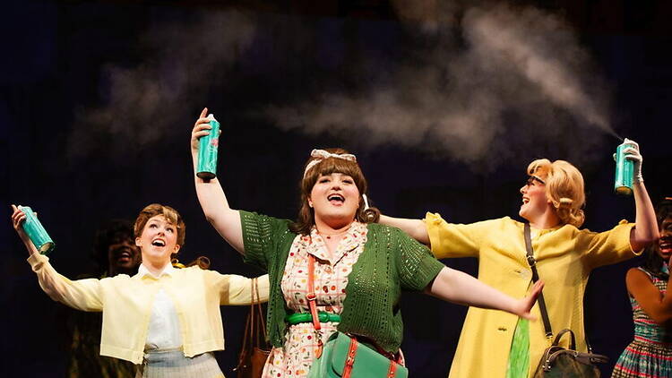 A wide shot of performers singing and dancing on stage during a musical performance. A wide shot of performers singing and dancing on stage during a musical performance.