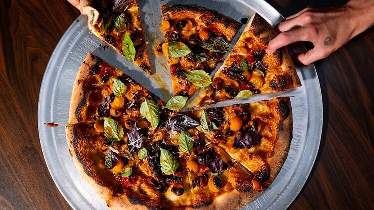 The Lineup | People grabbing at pizza slices on a metal tray