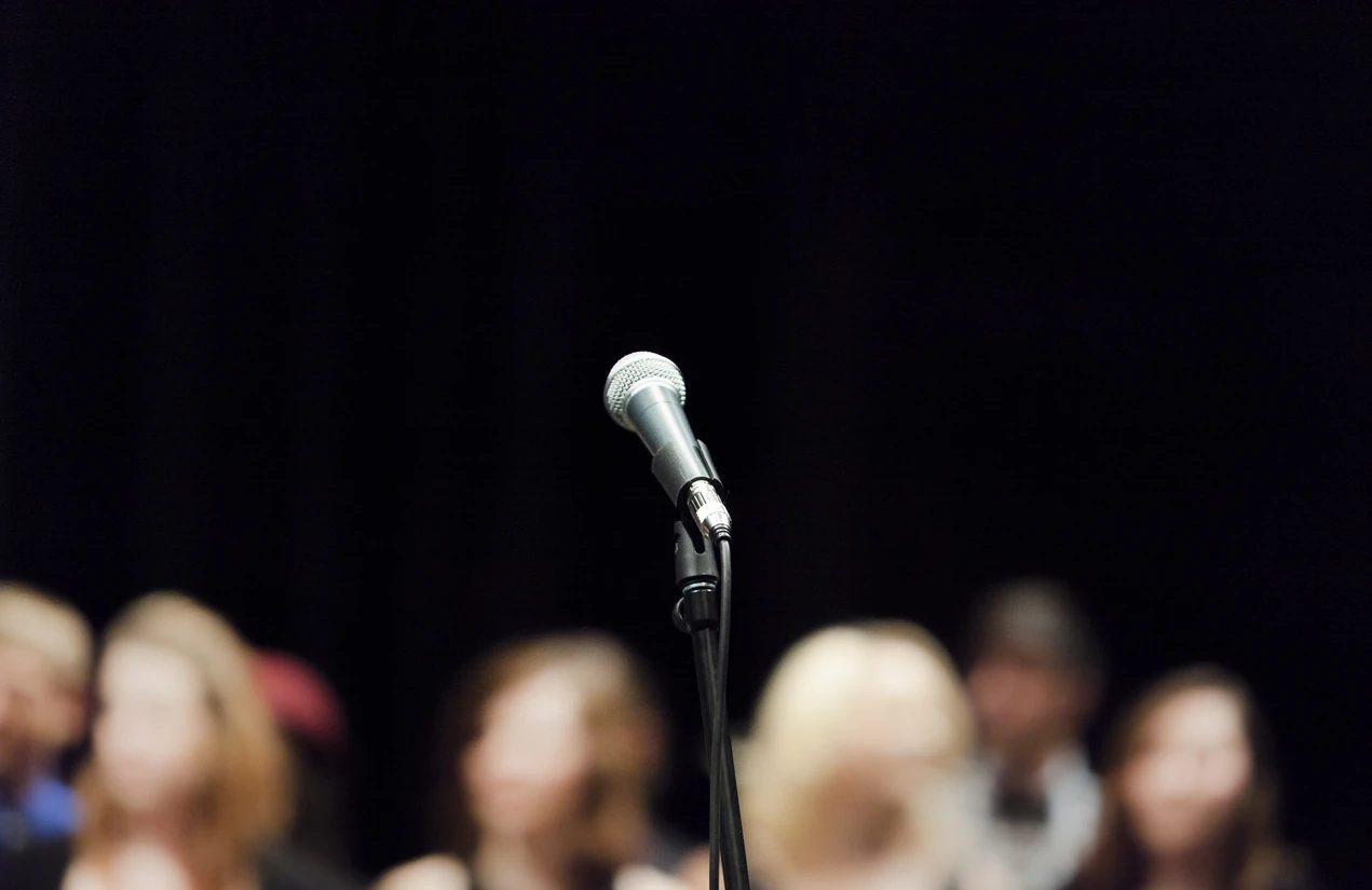 Vacant microphone ready to be used in front of people on a stage. 