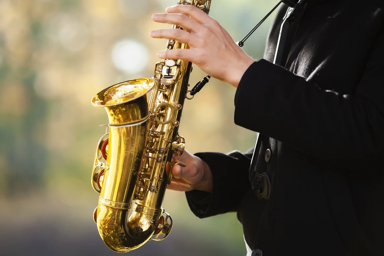 Autumn music: saxophonist's hands close up plays the saxophone in the autumn park