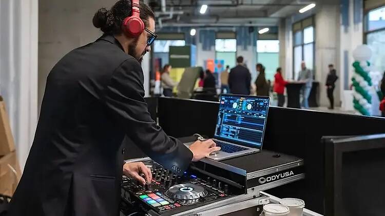 A close-up of a DJ operating audio equipment at an indoor event. A close-up of a DJ operating audio equipment at an indoor event.