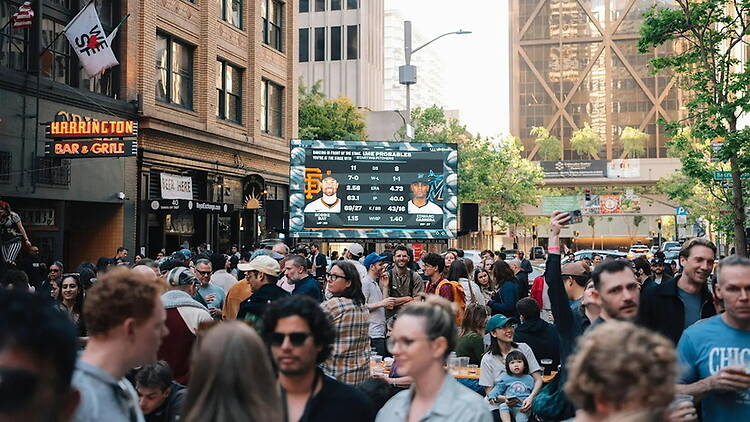 Wide view of people gathering for an outdoor event on a city street. Wide view of people gathering for an outdoor event on a city street.
