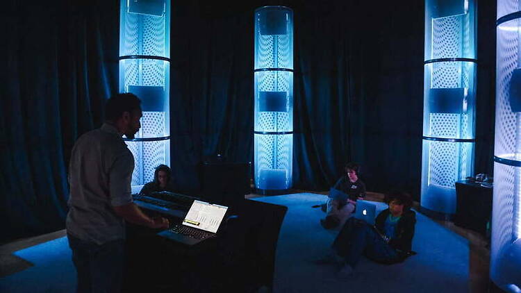 Wide view of people using computers in a dimly lit event space. Wide view of people using computers in a dimly lit event space.