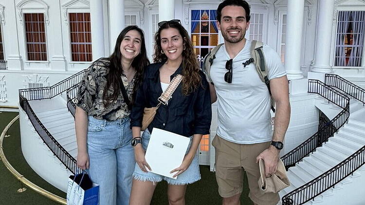 Close-up of three people posing for a photo outside a historic building. Close-up of three people posing for a photo outside a historic building.