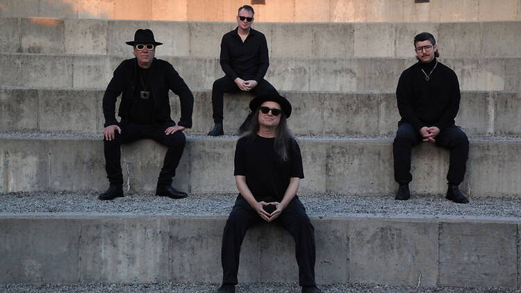 Wide view of four people posing on outdoor concrete steps. Wide view of four people posing on outdoor concrete steps.