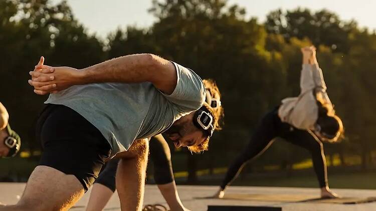 A close-up of people stretching during an outdoor fitness class in a park A close-up of people stretching during an outdoor fitness class in a park