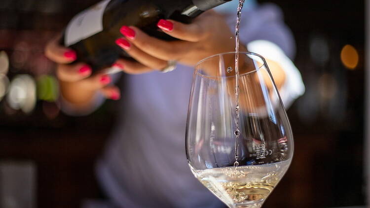 A close-up of wine being poured into a glass at a bar