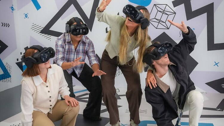 A wide shot of people wearing VR headsets exploring a virtual reality experience indoors