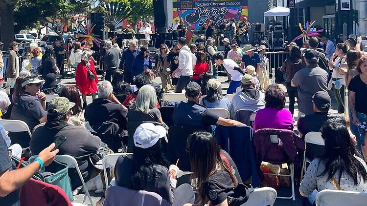 Wide view of people watching a live performance at an outdoor festival. Wide view of people watching a live performance at an outdoor festival.
