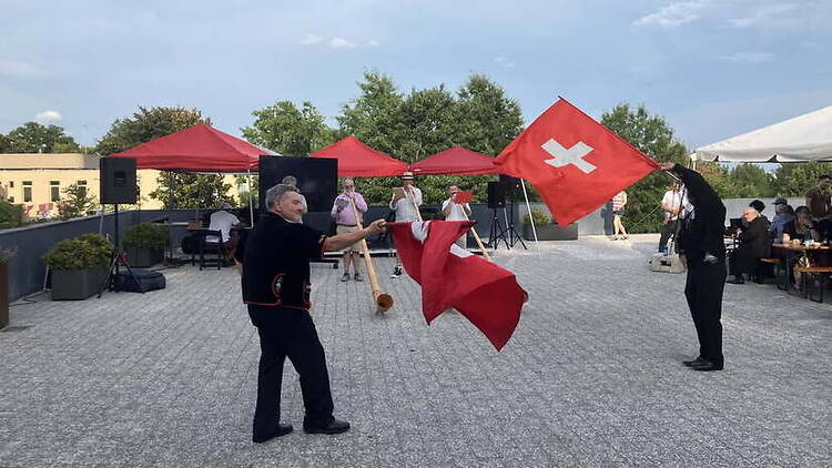 Wide view of performers waving flags at an outdoor cultural event.