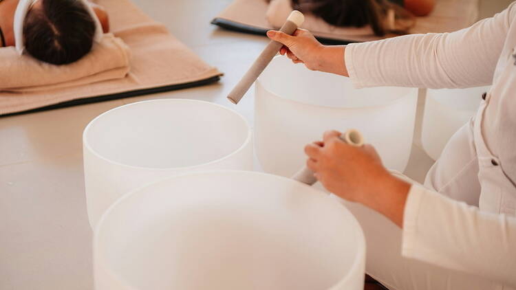 Close-up of person playing singing bowls in a wellness studio. Close-up of person playing singing bowls in a wellness studio.