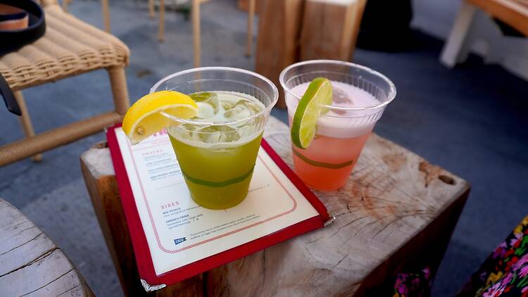 Two drinks, one green and one pink, sitting on a wooden table