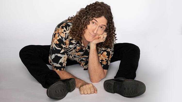 A wide shot of a person sitting on the floor and posing against a white studio backdrop A wide shot of a person sitting on the floor and posing against a white studio backdrop