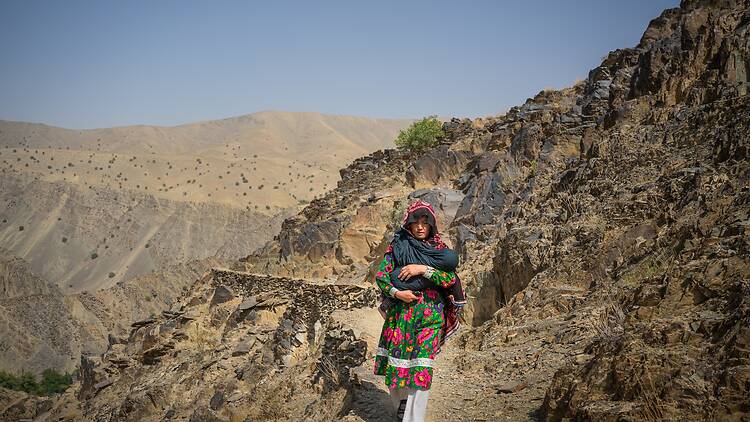 “I’m Afraid”: Afghan Women Face US Aid Cuts A pregnant woman walks in a hilly region in Afghanistan.