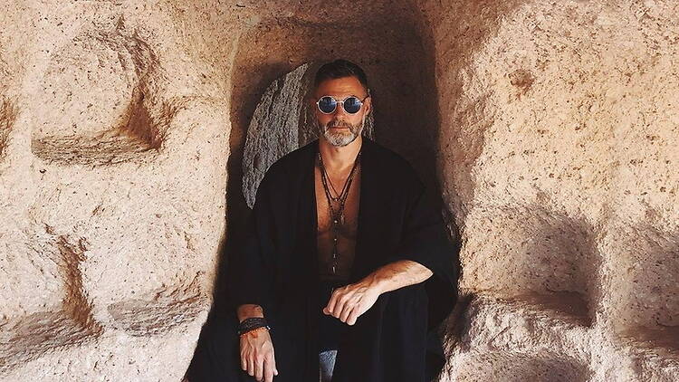 Close-up of a person sitting inside a carved stone cave opening. Close-up of a person sitting inside a carved stone cave opening.