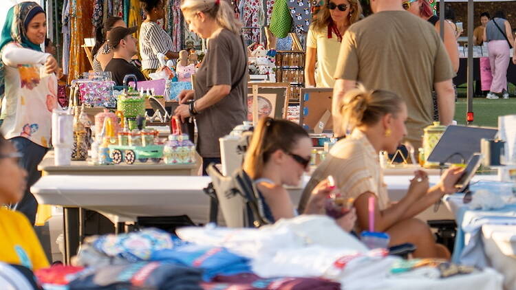 A wide shot of people shopping at vendor stalls during an outdoor festival. A wide shot of people shopping at vendor stalls during an outdoor festival.