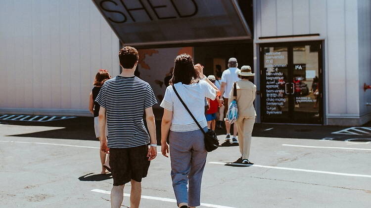 A wide shot of visitors walking toward a museum entrance.