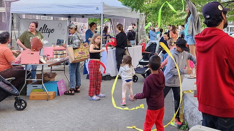 A wide shot of people watching a movie in a dark theater. A wide shot of children playing with ribbons at an outdoor community festival.
