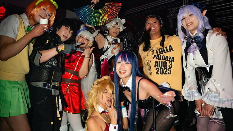 A wide shot of people posing in cosplay costumes at an indoor fan event. A wide shot of people posing in cosplay costumes at an indoor fan event.