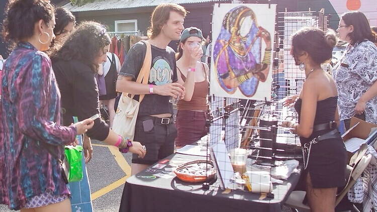 A wide shot of people browsing artwork at an outdoor market. A wide shot of people browsing artwork at an outdoor market.