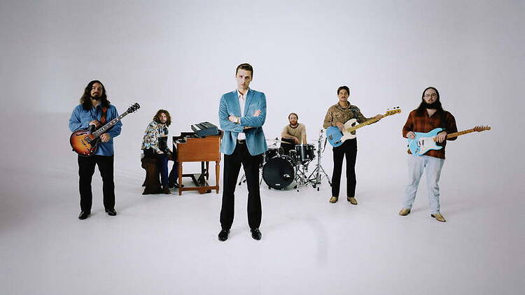 A wide shot of a band posing with instruments in a studio. A wide shot of a band posing with instruments in a studio.