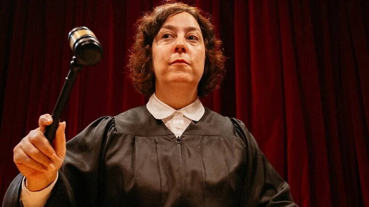 Close-up of a judge holding a gavel on a courtroom stage. Close-up of a judge holding a gavel on a courtroom stage.