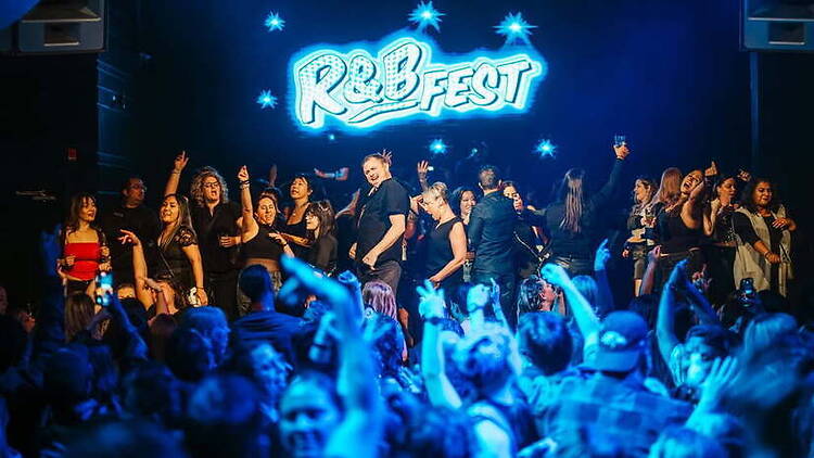 A wide shot of people dancing on stage during a live music event. A wide shot of people dancing on stage during a live music event.