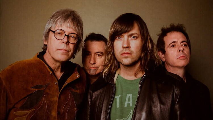 Close-up of four people posing for a group portrait against a plain background.