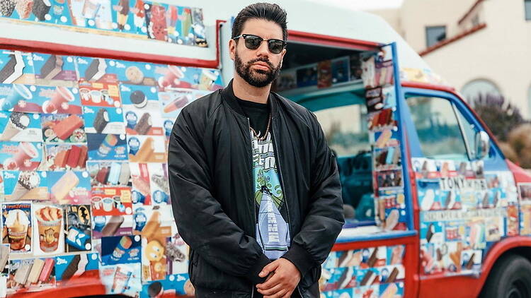 A medium shot of a person standing in front of an ice cream truck