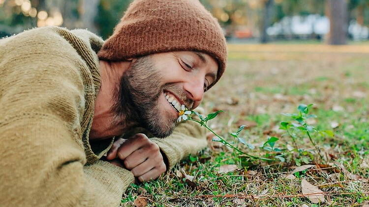 Close-up of person smelling a flower in a park. Close-up of person smelling a flower in a park.