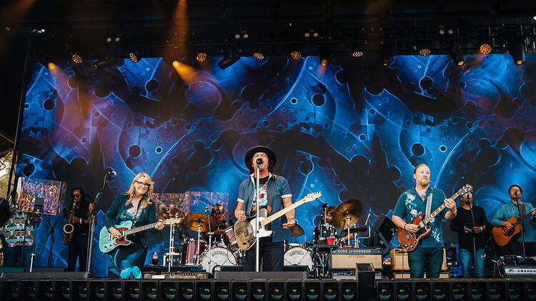 A wide shot of a band performing on an outdoor stage A wide shot of a band performing on an outdoor stage