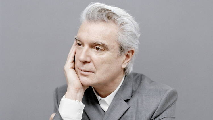 A close-up of a person resting their face on a hand against a plain background A close-up of a person resting their face on a hand against a plain background
