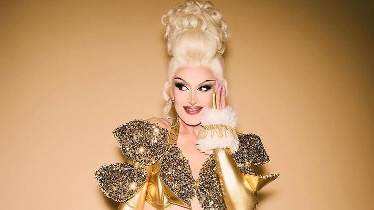 A person posing against a gold backdrop A person posing against a gold backdrop