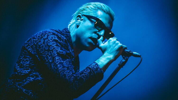 A close-up of a person singing into a microphone on a stage