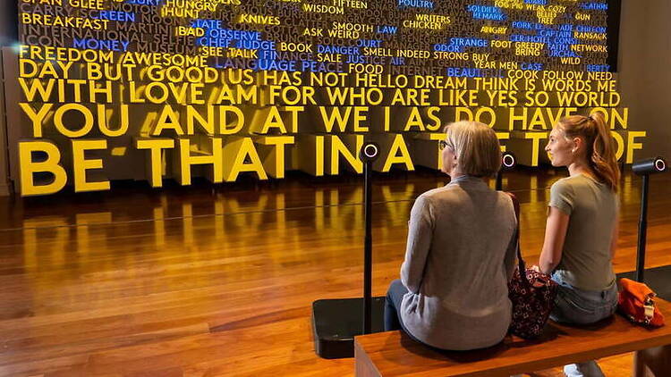 Wide view of two people viewing a word art display in a museum. Wide view of two people viewing a word art display in a museum.
