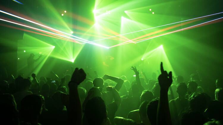 A wide shot of a crowd dancing under stage lights A wide shot of a crowd dancing under stage lights