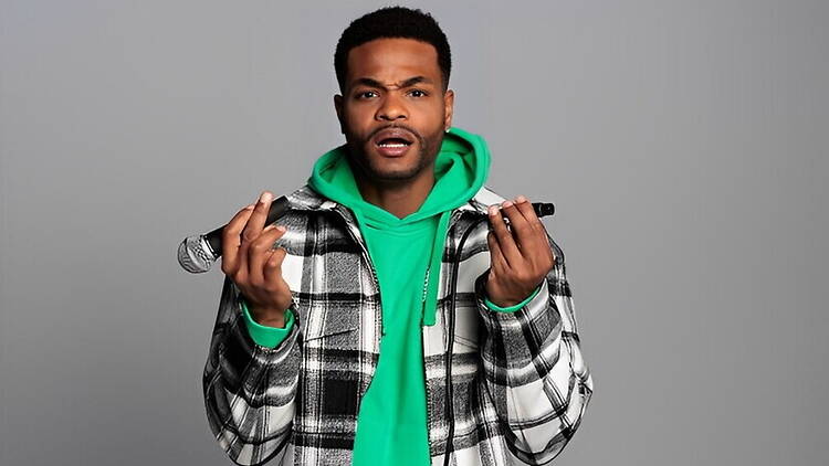 A person holding a microphone against a plain background A person holding a microphone against a plain background