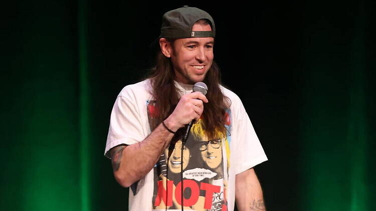 A close-up of a comedian holding a microphone on a stage. A close-up of a comedian holding a microphone on a stage.