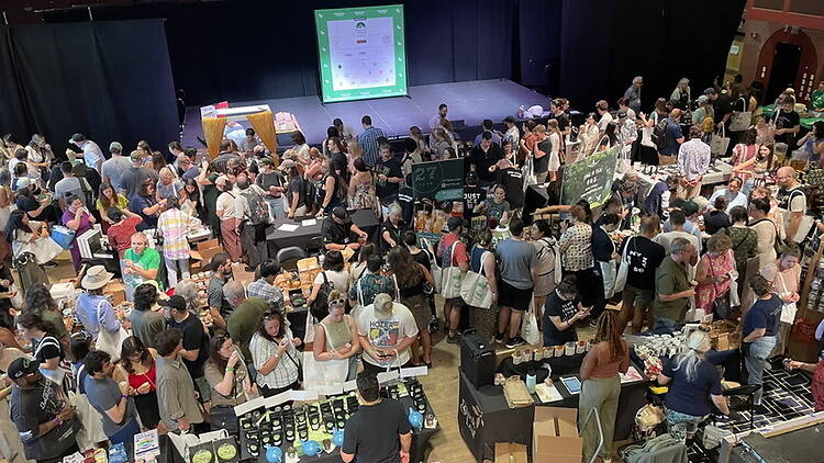 A wide shot of people browsing vendor booths at an indoor expo. A wide shot of people browsing vendor booths at an indoor expo.