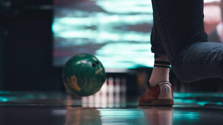 A close-up of a bowler releasing a bowling ball at a bowling alley. A close-up of a bowler releasing a bowling ball at a bowling alley.