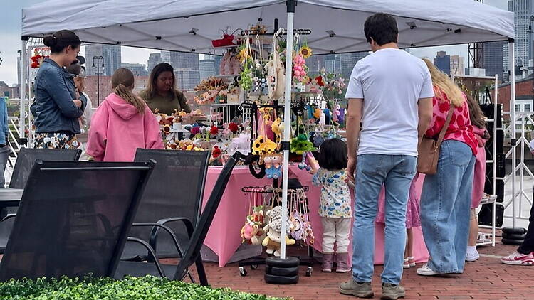 A wide shot of people browsing handmade crafts at an outdoor market. A wide shot of people browsing handmade crafts at an outdoor market.