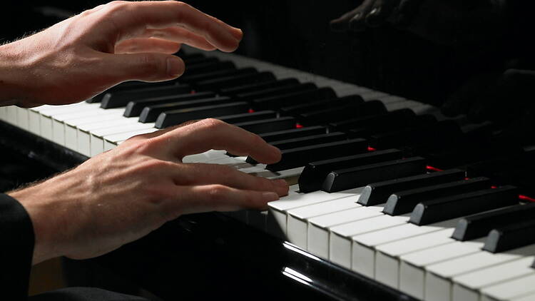 A close-up of hands playing a piano on a keyboard. A close-up of hands playing a piano on a keyboard.