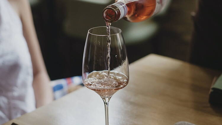 A close-up of wine pouring into a glass on a table. A close-up of wine pouring into a glass on a table.