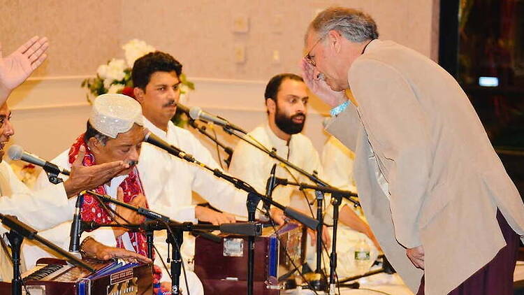 A wide shot of musicians performing at an indoor cultural event. A wide shot of musicians performing at an indoor cultural event.