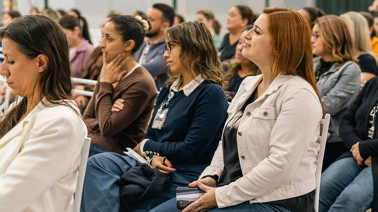 A wide shot of people listening to a speaker at an indoor event. A wide shot of people listening to a speaker at an indoor event.