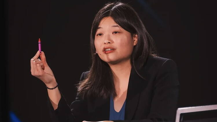 A close-up of a speaker holding a marker while presenting on stage. A close-up of a speaker holding a marker while presenting on stage.